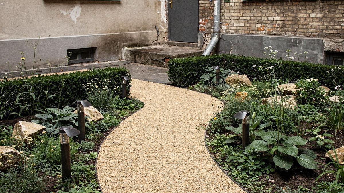 Renovated courtyard garden with clipped hedges, gravel path and low bollard lighting
